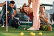 © Zoran Zeremski - Group of smiling friends enjoying together playing mini golf in the city.