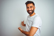 Young indian man wearing t-shirt standing over isolated white background Inviting to enter smiling natural with open hand