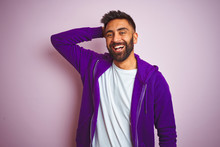 Young Indian Man Wearing Purple Sweatshirt Standing Over Isolated Pink Background Smiling Confident Touching Hair With Hand Up Gesture, Posing Attractive And Fashionable