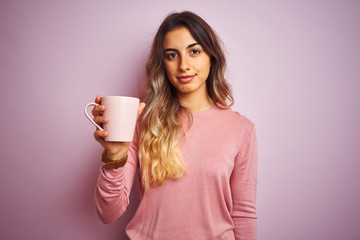 Poster - Young beautiful woman holding cup of coffee over pink isolated background with a confident expression on smart face thinking serious