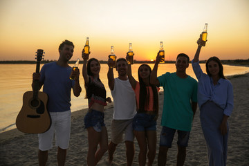 Canvas Print - Silhouette of friends drinking beer on sea beach at sunset