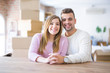 © Krakenimages.com - Young beautiful couple sitting on the table at home, hugging in love very happy for moving to new home with cardboard boxes behind them