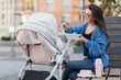 © Тарас Нагирняк - Mother walking with hewborn baby in stroller, woman holding plastic box and feeding her baby.