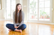© Krakenimages.com - Beautiful Asian woman sitting barefoot on the floor at home looking away to side with smile on face, natural expression. Laughing confident.