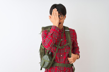 Sticker - Chinese hiker man wearing backpack canteen glasses over isolated white background covering one eye with hand, confident smile on face and surprise emotion.