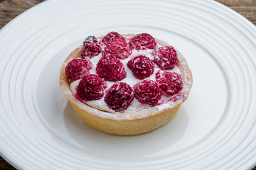 Wall Mural - raspberry tartlet on a plate on wooden table