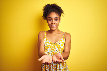 Sticker - African american woman wearing casual floral dress standing over isolated yellow background Smiling with hands palms together receiving or giving gesture. Hold and protection