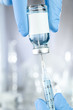 Healthcare concept with a hand in blue medical gloves holding a vaccine vial with blue liquid and black white label