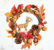Festive autumn Thanksgiving wreath with deer toy, fall leaves, red berries, acorns on light background. autumn holiday, thanksgiving, halloween concept. Flat lay, top view