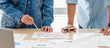 © weedezign - close up hand asian creative designer team casual meeting and brainstorming on desk with paperwork and online data on laptop in meeting room at modern office.business planning concept