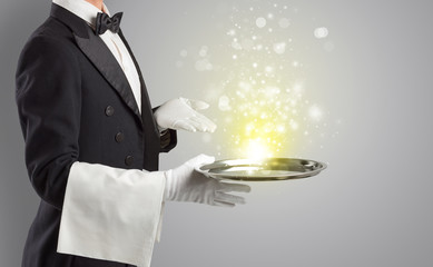 Elegant young waiter serving mysterious light on tray