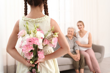 Wall Mural - Girl congratulating her mom and grandmother in living room, closeup