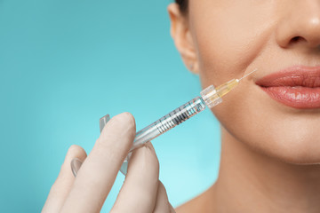 Poster - Beautiful woman getting facial injection on light blue background, closeup. Cosmetic surgery