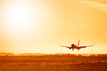 The plane lands at the airport at sunset