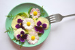 Elite cuisine: edible flowers. The concept of eco-friendly nutrition, vegetarianism, healthy lifestyle, diet. Plate with salad with edible flowers daisies and pansies