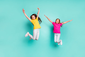 Full length body size photo of two enjoying girls being free wearing yellow and pink t-shirts while isolated with teal background