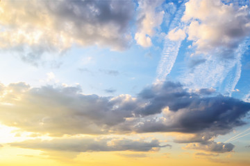 Wall Mural - evening skyscape with wide airplane traces. blue sky and clouds are colored with golden yellow color