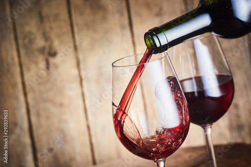 Cuadros en Lienzo A glass of dry red wine being poured from a bottle
