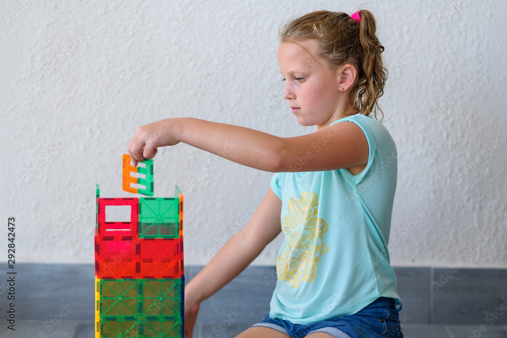 Beautiful teenage girl playing with lots of colorful plastic blocks ...