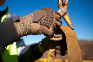 Wall Mural - Rigger high risk worker wearing heavy duty glove and clipping a safety crane hook into  three tones yellow lifting sling prior to lift in construction mine site Perth city, Australia 