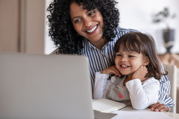busy mother and entrepreneur using a laptop with her daughter