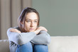 Depressed young woman on sofa at home.