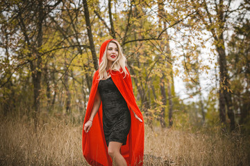 Concept of Halloween. Beautiful and simple costume of little red hood. Mysterious hooded figure in misty forest. Girl in red raincoat. Cosplay Fairy Tale Little Red Riding Hood 