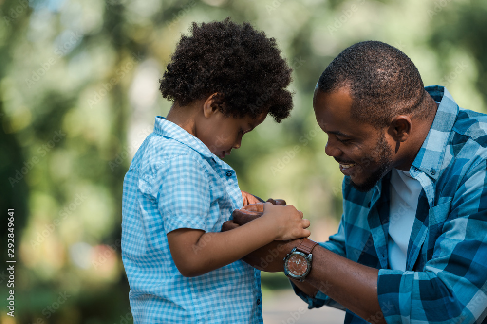 side view of cheerful african american father holding hands with sad ...