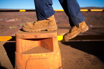 Wall Mural - Miner worker wearing heavy duty steel cap boot using safety step white working at height to preventing from falling at construction mine site Perth, Australia