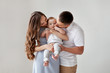 © Anna Zhukkova - Happy young family. Beautiful Mother and father kissing their baby . Parents, Portrait of Mom, dad and smiling child on hands isolated over white background.