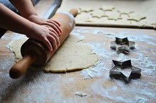Roll The Dough For Christmas Cookies In Form Of Stars By Little Hands Of Girl. Preparation For Christmas. Close Up.