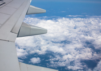 View through the window of an airplane wing against the blue sky.