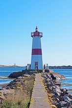 Connected To The Shore By A Narrow Causeway, A Red And White Lighthouse Can Be Found In The Harbor Of St. Pierre In The French Territory Of St. Pierre And Miquelon.