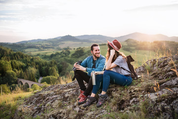 Wall Mural - young tourist couple travellers with binoculars hiking in nature, resting.