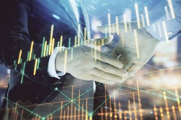 Double exposure of financial chart on cityscape background with two businessmen handshake. Concept of financial analysis and investment opportunities