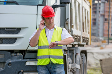 construction site engineer looking at the time on his watch.