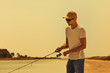 © producer - Young man fishing at sea from the shore. fisherman uses spinning