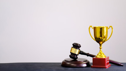 Judge's gavel and trophy on white background. Symbol for jurisdiction. Law concept a wooden judges gavel on table in a courtroom or law enforcement office