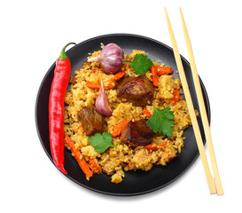 Wall Mural - pilaf with meat and chili pepper on black plate isolated on white background. top view