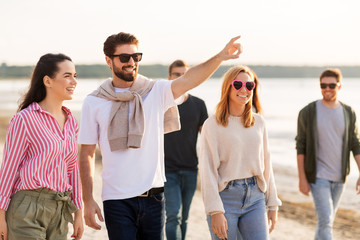 Poster - friendship, leisure and people concept - group of happy friends walking along beach in summer