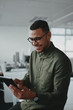 © StratfordProductions - Handsome young african american businessman sitting in office smiling while using a smartphone