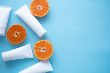 Whites Cosmetic bottle containers, fresh citrus on blue background top view flat lay copy space. Blank label for branding mock-up Natural beauty product concept.