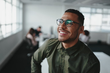 portrait of a handsome casual businessman wearing black eyeglasses in office smiling