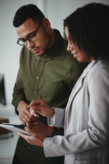 Wall Mural - Young african american businessman and businesswoman discussing project on digital tablet computer in office