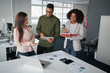© StratfordProductions - Multiethnic coworkers team working new startup project at modern office analyzing business documents, using digital tablet and mobile phone