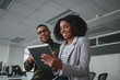 © StratfordProductions - Portrait of smiling professional young African American businesswoman showing data on digital tablet to male colleague in office