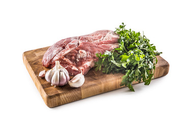 Pork neck raw meat with garlic parsley herbs tomatoes and rosemary on butcher board isolated on white background