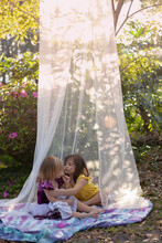 Two Little Girls Playing Outside And Reading Books In The Yard In A Shade Tent With Balloons