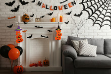 Halloween Decorations On White Fireplace And Grey Couch With Orange Pumpkins And Balloons