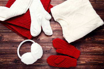 Wall Mural - Knitted sweater with scarf, pair of gloves, socks and earmuffs on wooden table